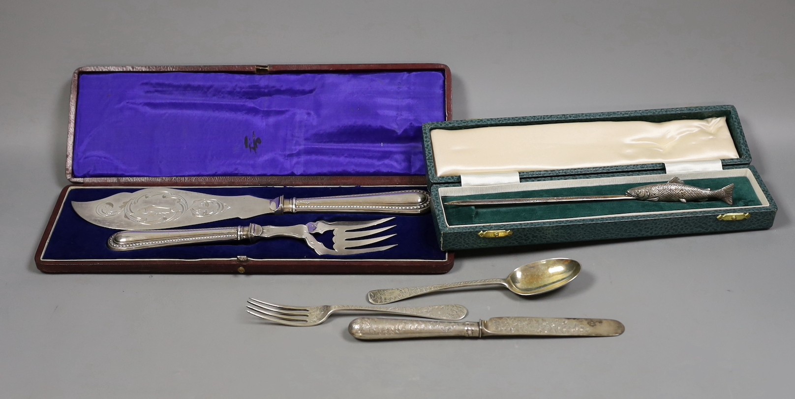 A late Victorian engraved silver christening trio, Wakely & Wheeler, London, 1889/90, a cased novelty silver letter opener, with fish handle, C.J. Vander Ltd, London, 1971 and a cased pair of silver plated fish servers.